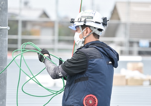 ヘルメットを着用し、配線作業を行う作業員